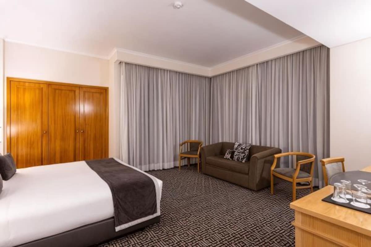 Una habitación de hotel con cama, sofá, mesa de comedor y armario.