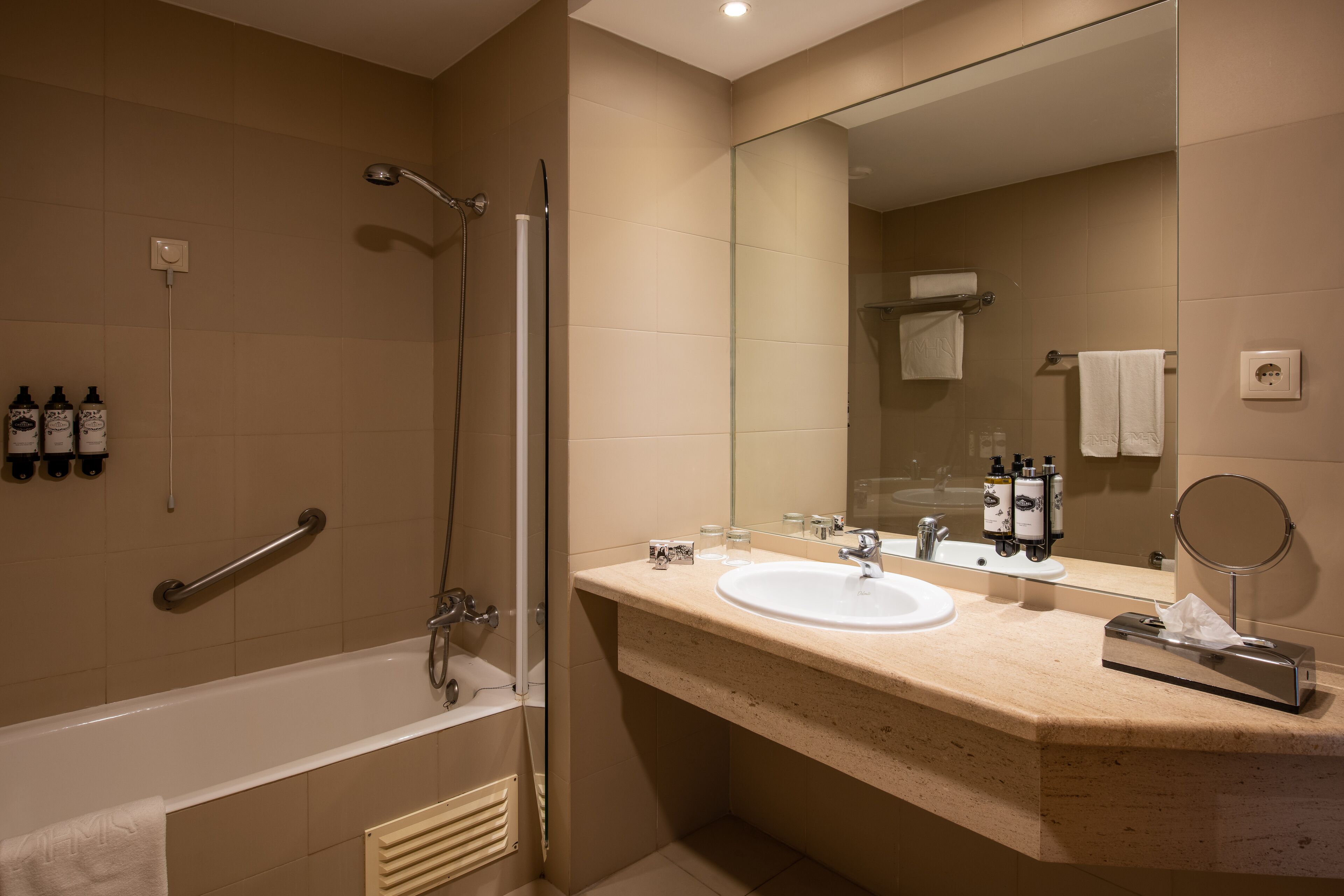 A modern bathroom with a bathtub, a shower, a sink, and a large mirror.