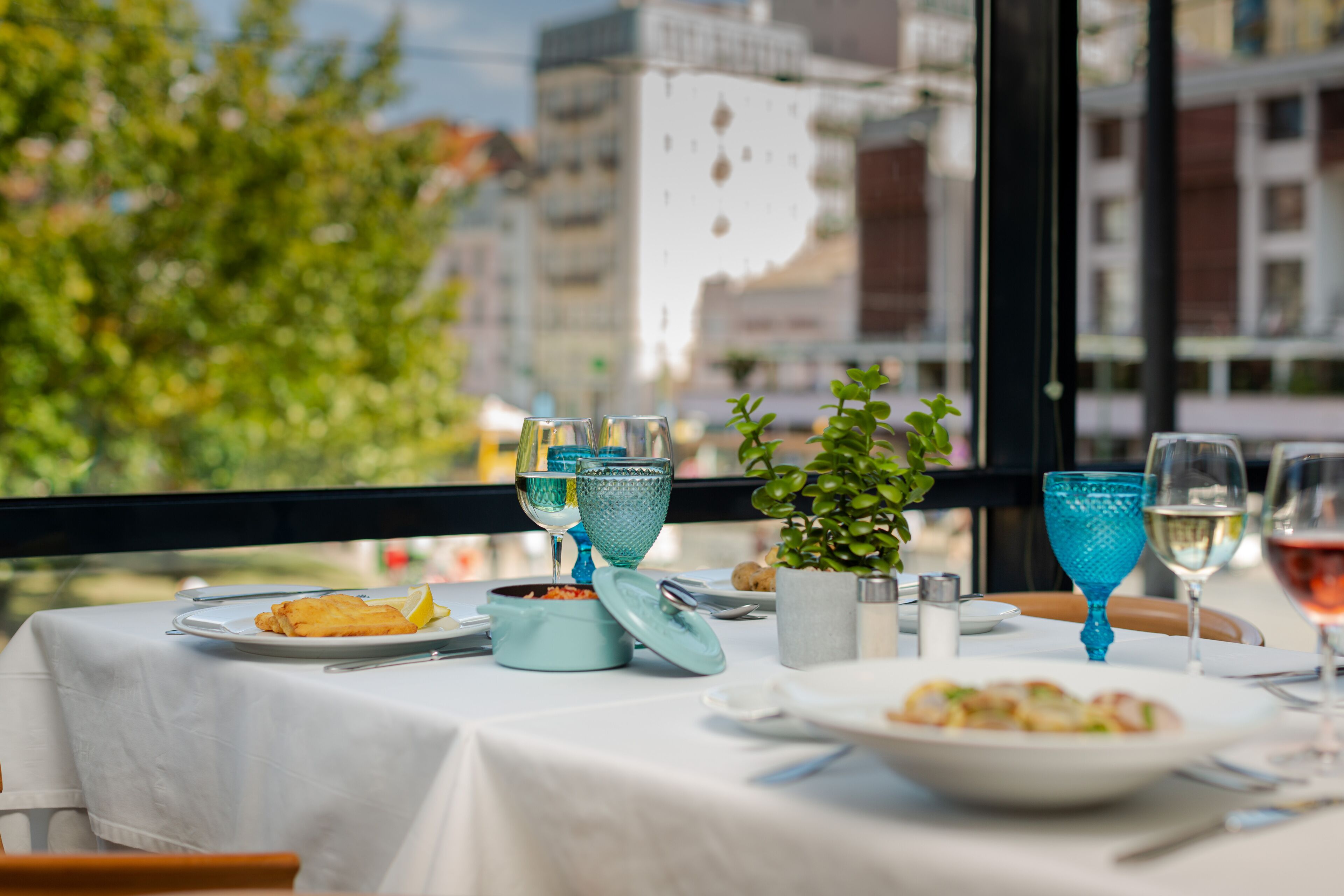 Una mesa de comedor dispuesta con platos, vasos y una planta pequeña.