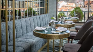 A modern dining area with a sofa and two round tables, each with a small plant and set for dining.