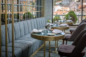 A modern dining area with a sofa and two round tables, each with a small plant and set for dining.