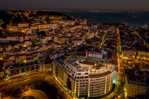Une vue nocturne d’un paysage urbain historique, avec un bâtiment circulaire imposant doté d’une cour intérieure.