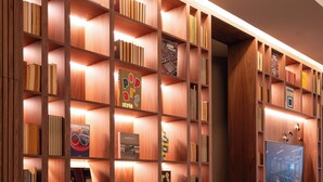 Una biblioteca con estanterías de madera y una pantalla de televisión.
