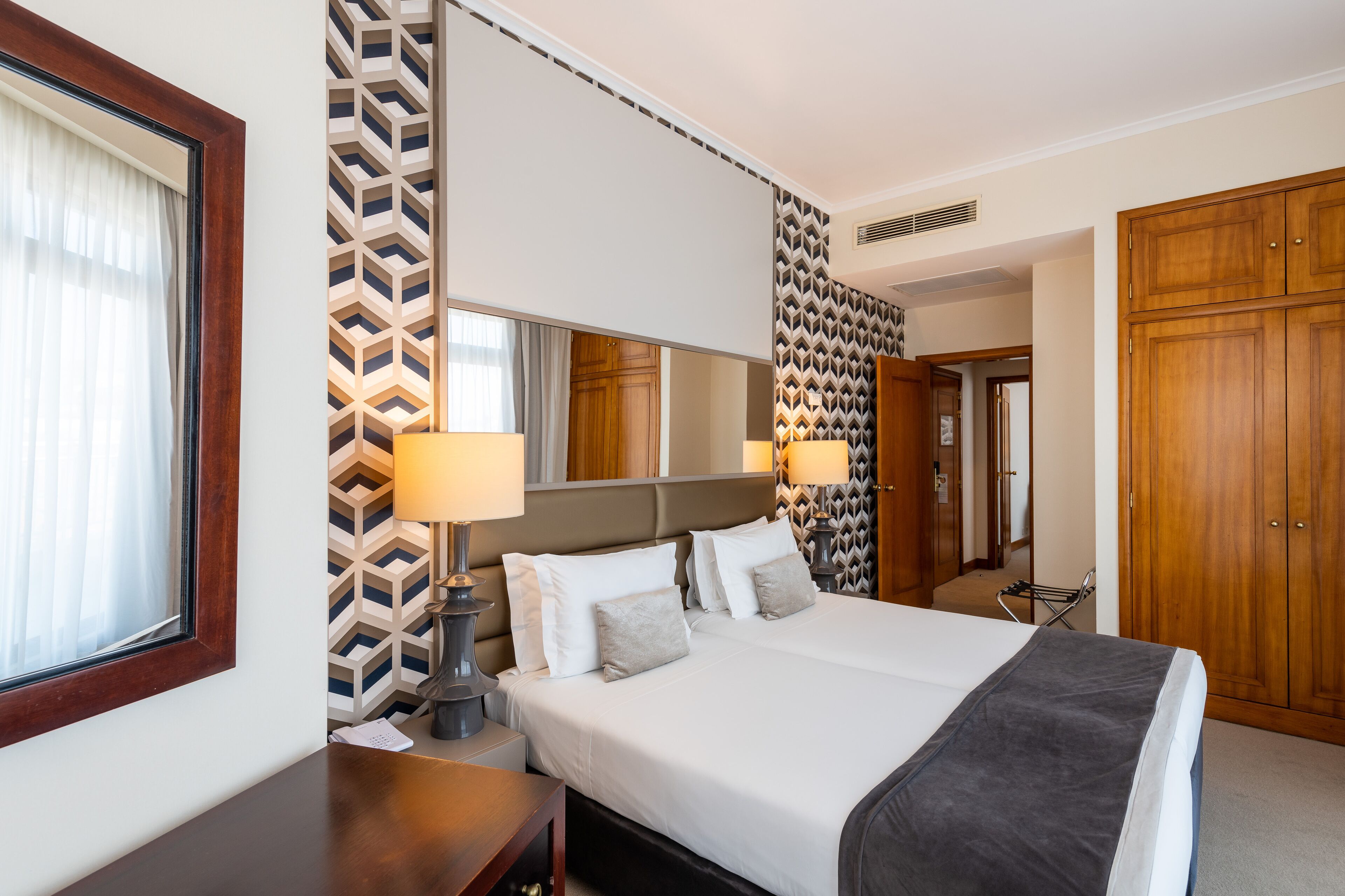 Ein Hotelzimmer mit einem großen Bett, zwei Nachttischen, einem Spiegel und einem Kleiderschrank.