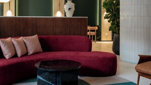 Un moderno vestíbulo con un sofá rojo, una mesa de centro negra y una gran planta en maceta.