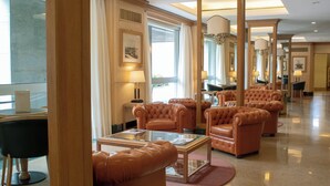 A spacious lobby with leather armchairs, a glass coffee table, and a large mirror reflecting the room. - Starhotels Vespucci (Campi Bisenzio)