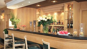 A bar area with a wooden counter, bar stools, and a variety of bottles and glasses. - Starhotels Vespucci (Campi Bisenzio)