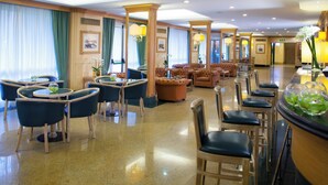 A hotel lobby with round tables, chairs, a bar area, and a seating area with sofas and armchairs. - Starhotels Vespucci (Campi Bisenzio)