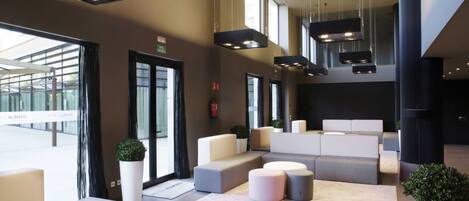 Un hall d’entrée moderne avec des espaces de détente, de grandes fenêtres et un comptoir d’accueil.