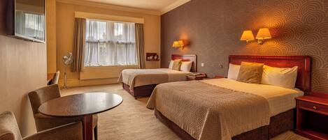 A hotel room with two beds, a round table, and a chair.