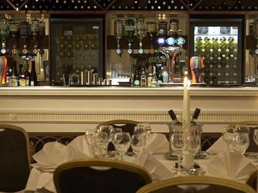 A bar area with a long counter, multiple taps, and a variety of bottles.