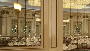 Un gran salón con paredes espejadas, candelabros y muebles ricamente decorados, reflejando un ambiente lujoso.