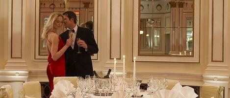 A formal dining setting with a table set for two, a candle centerpiece, and a mirror reflecting the room's decor.
