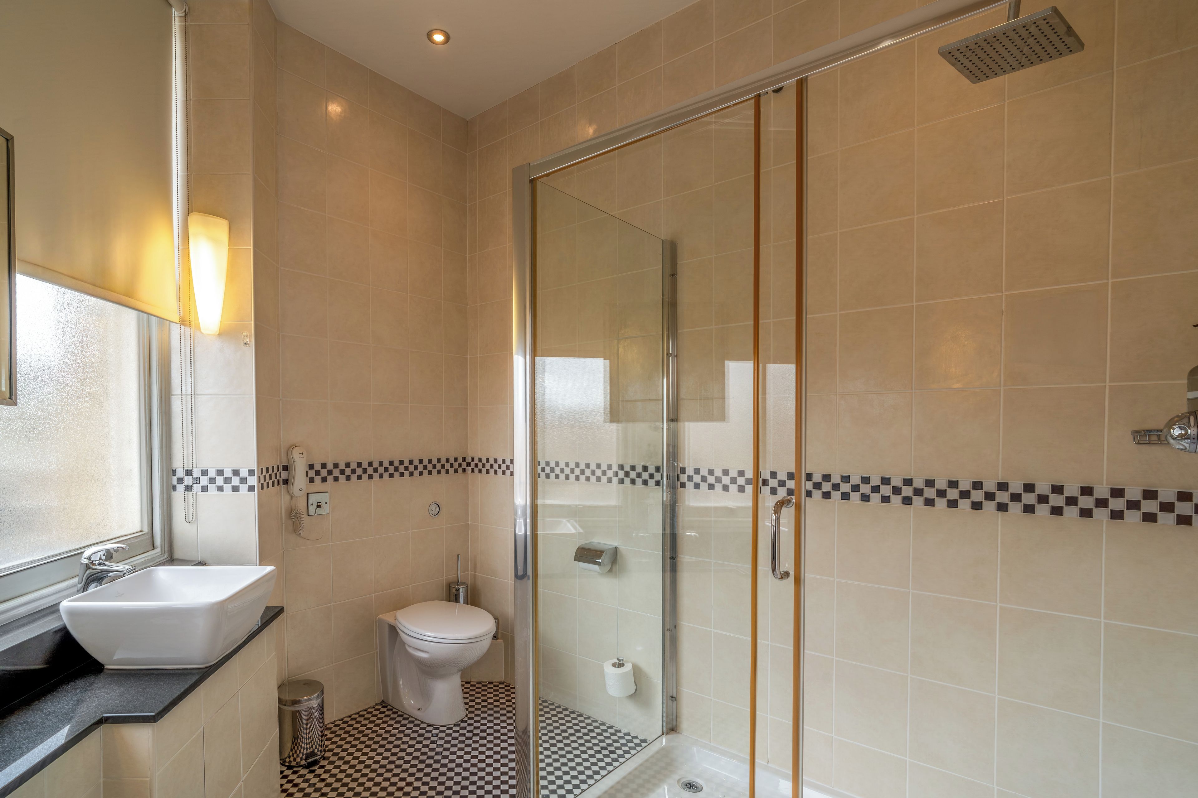 Un baño moderno con cabina de ducha de vidrio, inodoro y lavamanos.