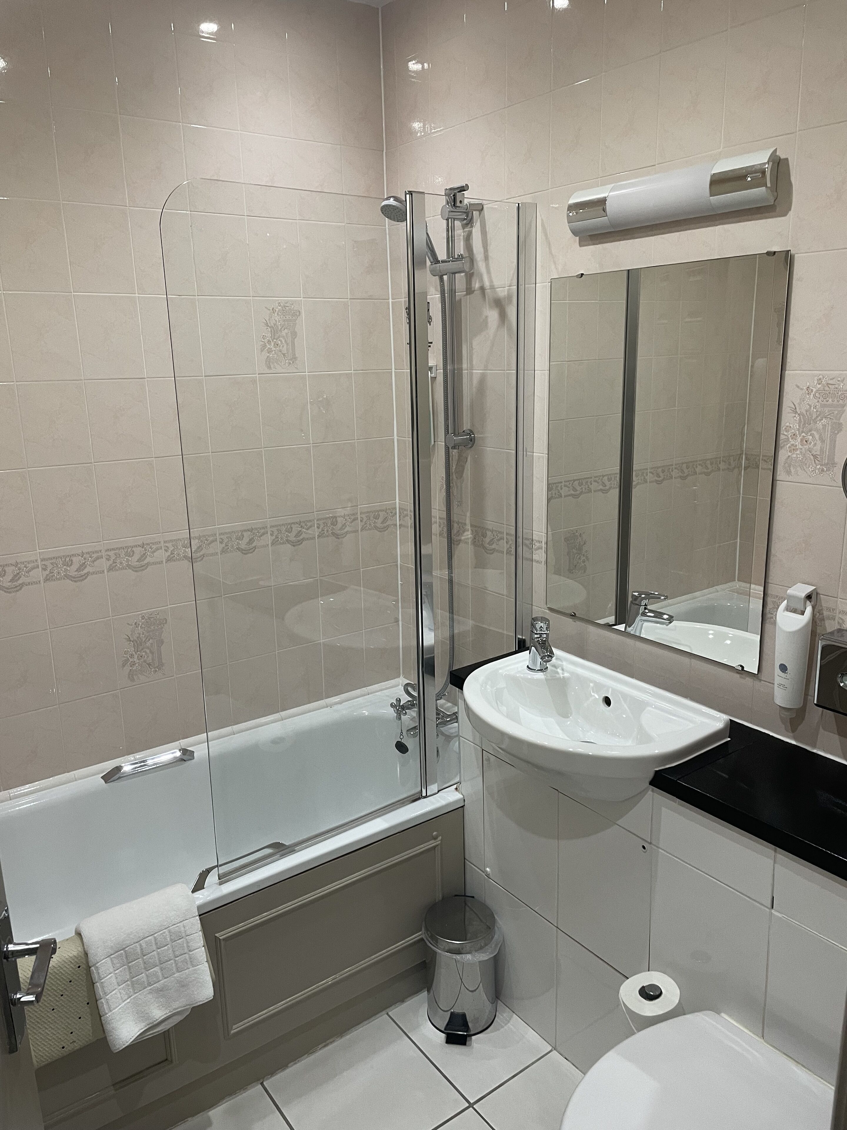 Un baño moderno con ducha de vidrio, lavamanos blanco y retrete.