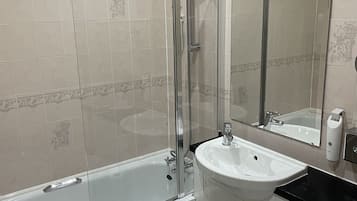 Un baño moderno con ducha de vidrio, lavamanos blanco y retrete.