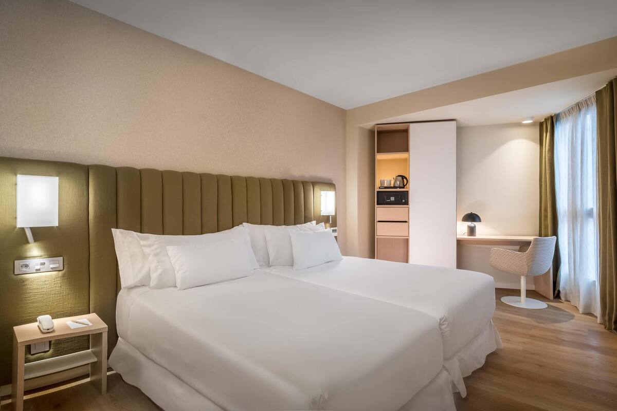 A hotel room with a large bed, bedside table, lamp, and a view of the bathroom.