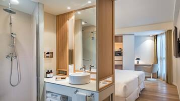 Un baño moderno con ducha a ras de suelo, un espejo grande y un tocador con artículos de aseo.