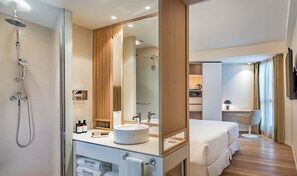 A modern bathroom with a walk-in shower, a large mirror, and a vanity with toiletries.