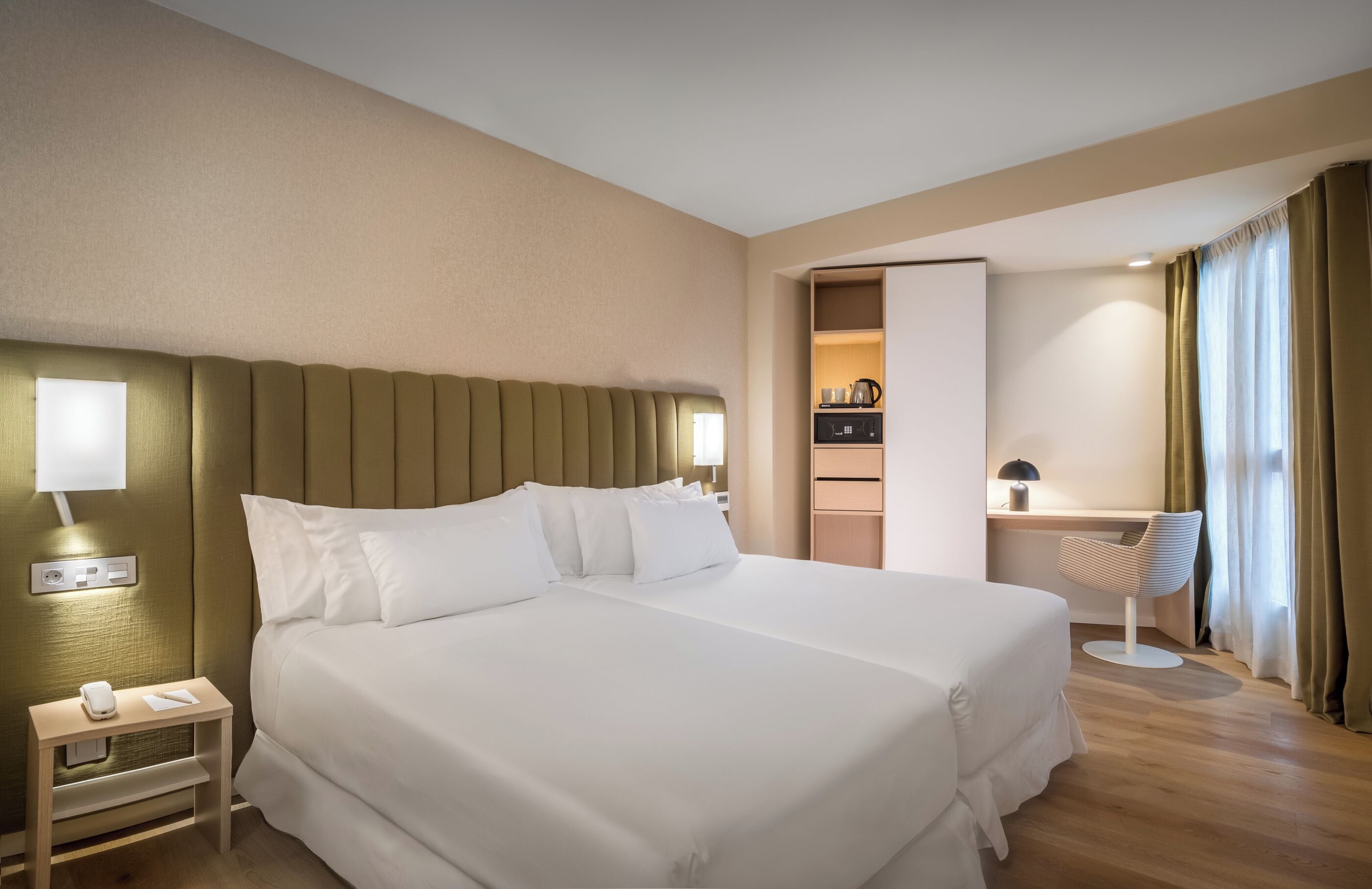 Habitación de hotel con una cama grande, mesitas de noche, un escritorio y una silla.