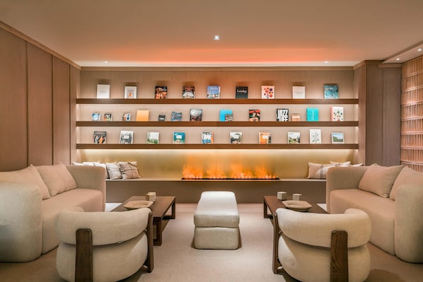Un moderno salón con chimenea, sofás y una estantería llena de libros de viajes.