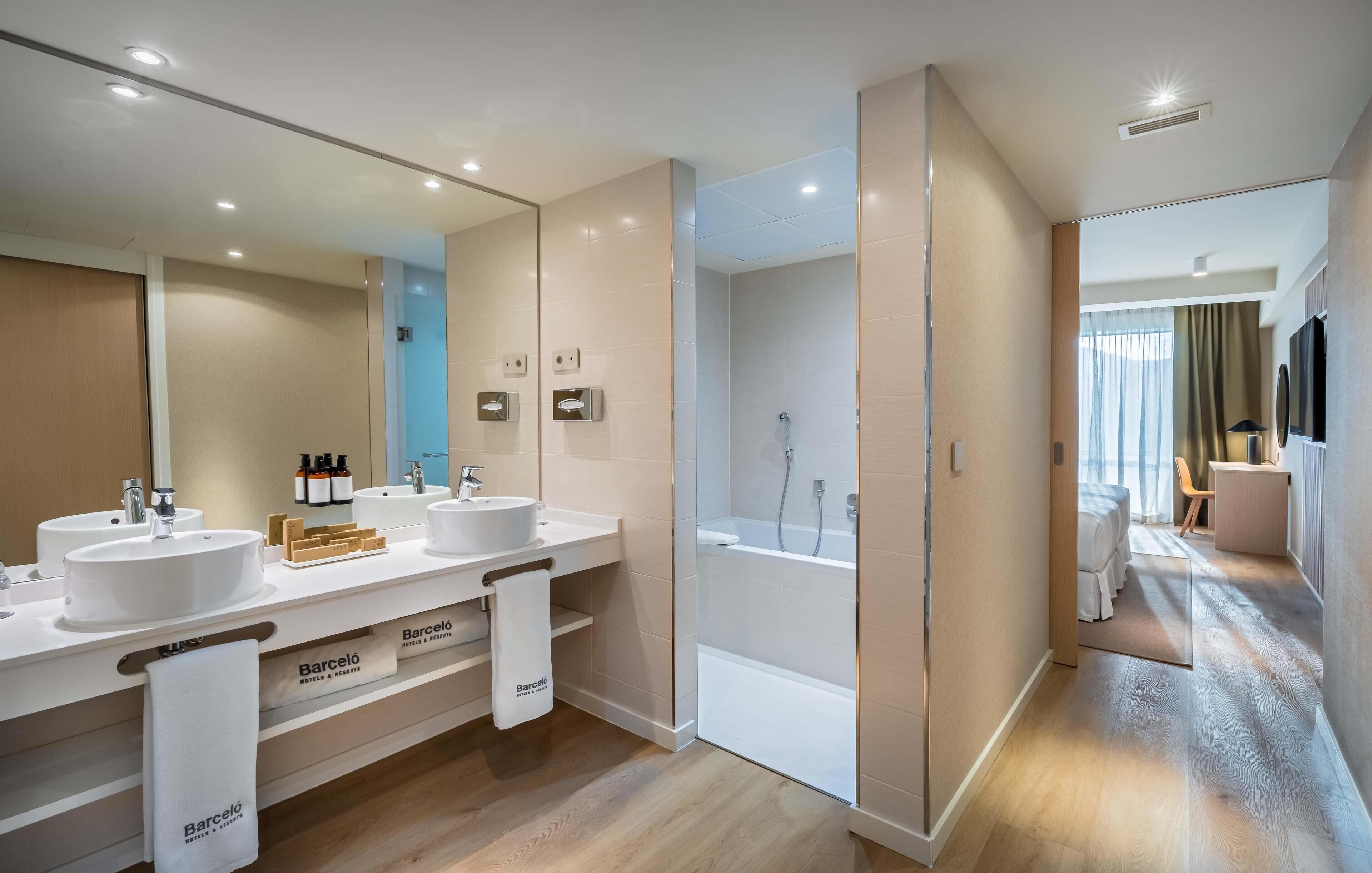 Un baño moderno con dos lavabos, ducha y un espejo grande.