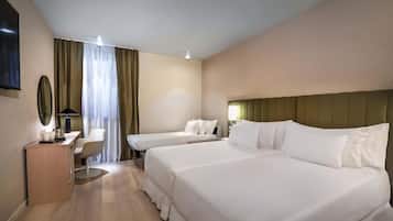 A hotel room with two beds, a desk with a lamp, a mirror, and a view of the outdoors through curtains.