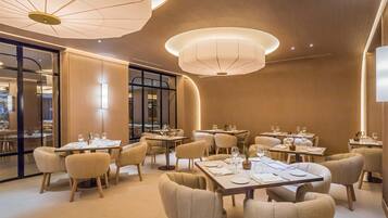 A modern dining area with round tables, beige chairs, and ambient lighting.