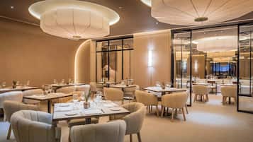 A modern restaurant interior with round tables, chairs, and ambient lighting.