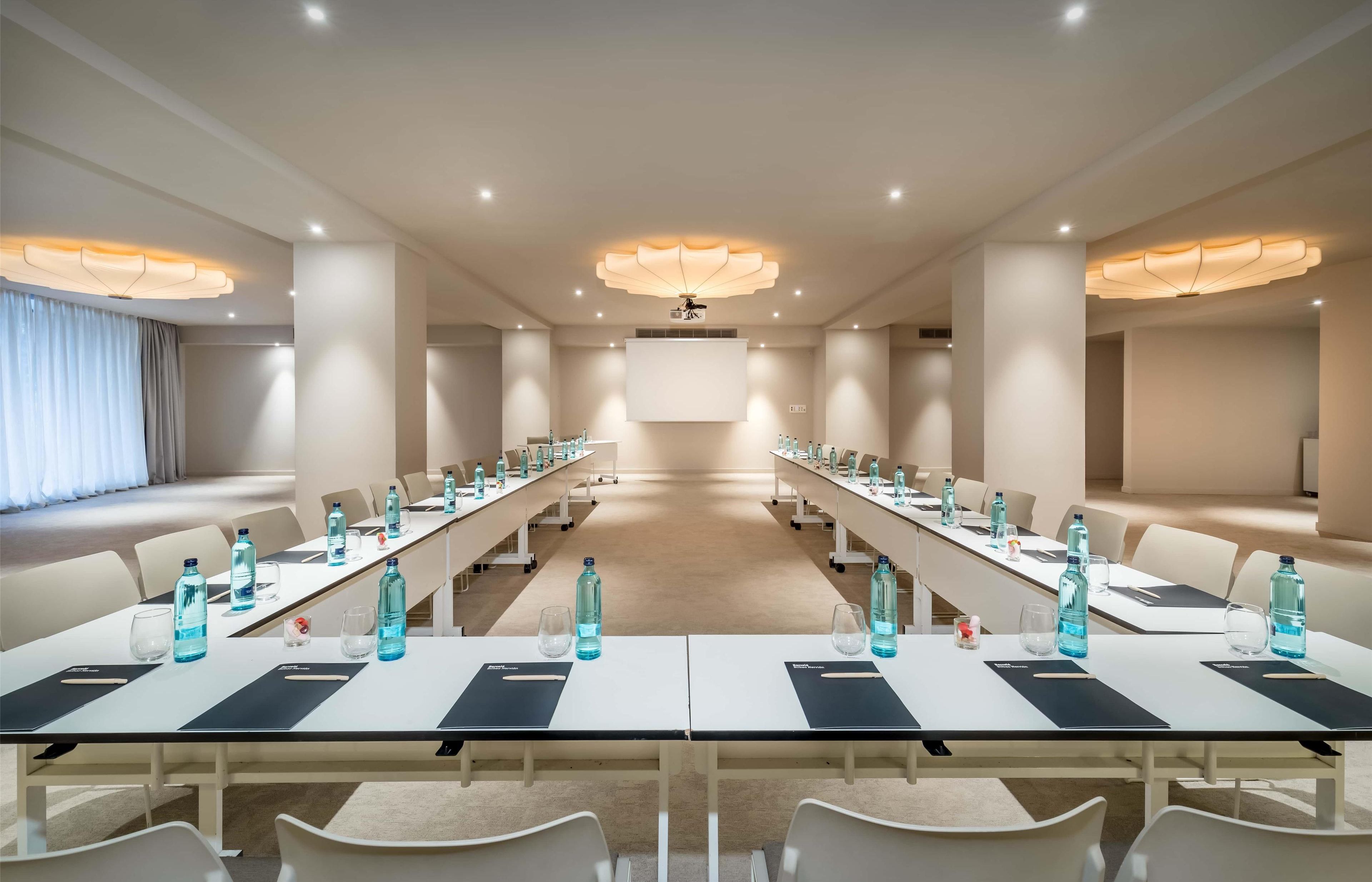 A conference room with long tables, chairs, water bottles, and nameplates.