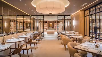 Un restaurante moderno con mesas redondas, sillas y una zona de bar central.