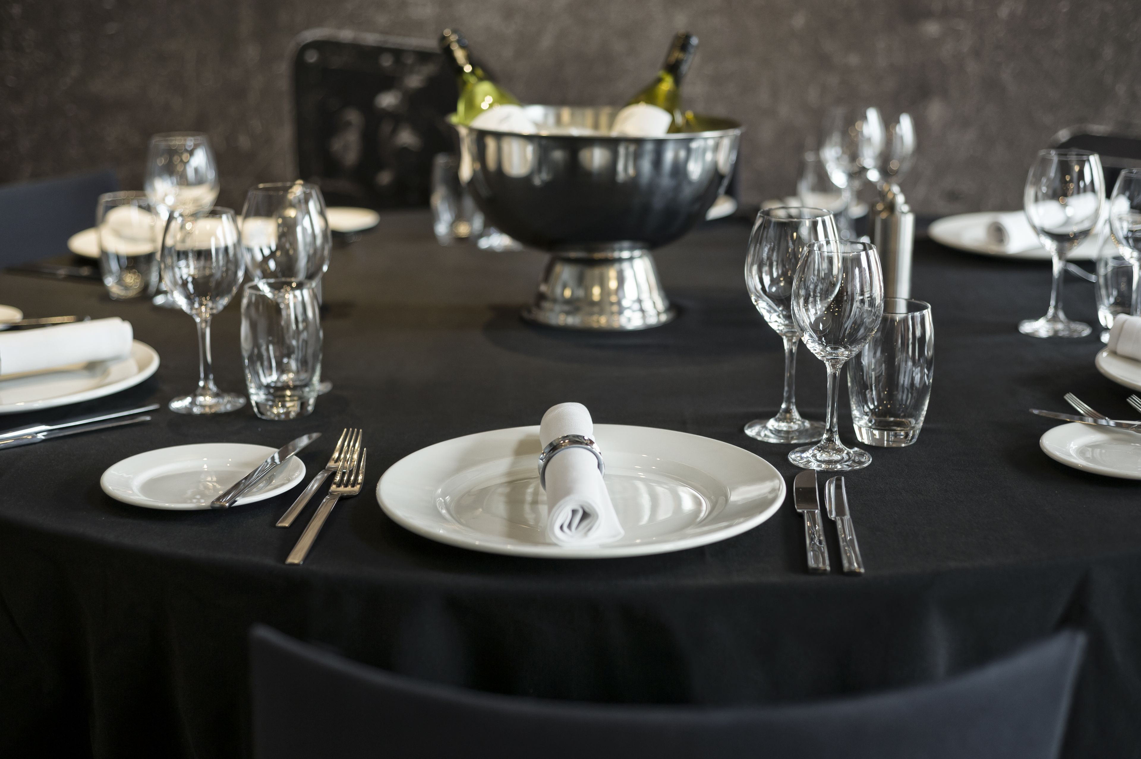 A table set for a formal dining experience with a silver bowl, wine glasses, and neatly arranged cutlery.