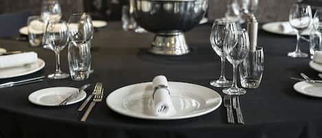 Ein Tisch, festlich für ein elegantes Abendessen gedeckt, mit einer Silber-Schüssel, Weingläsern und ordentlich drapiertem Besteck.
