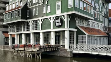 A green building with a sign reading "Intel Hotels." It features a covered outdoor seating area with tables and chairs.