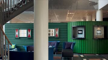 A lobby with a green wall, a staircase, and seating areas with cushions.