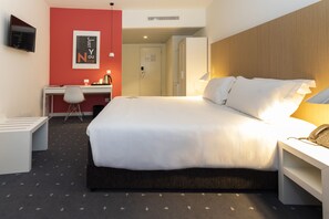 A hotel room with a large bed, a desk with a chair, a TV mounted on the wall, and a door leading to another room. - Stay Hotel Coimbra Centro (Coimbra)