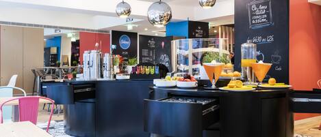 Een modern café met zwarte barkrukken, een centraal gelegen toonbank met een koffiemachine en een krijtbordmenu.