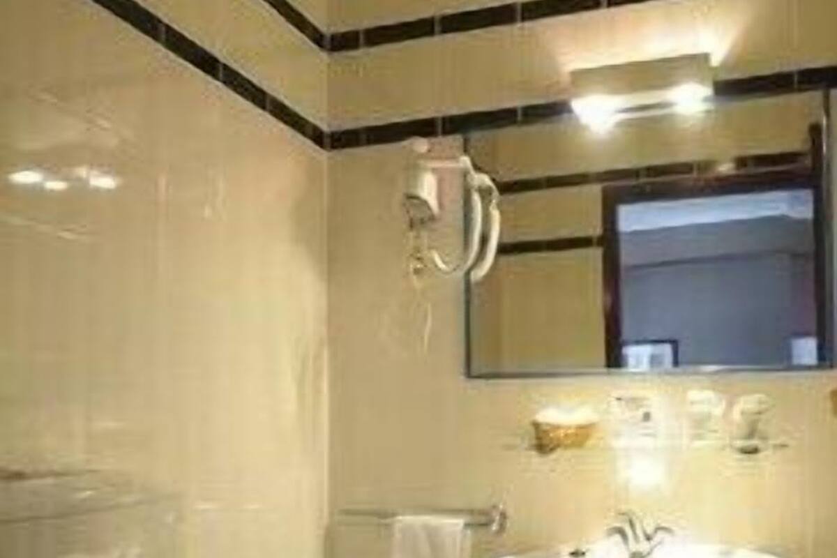 A bathroom with a toilet, sink, and mirror.