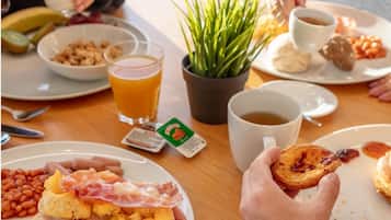 A breakfast setting with various dishes, including toast with eggs and bacon, beans, and a pastry.