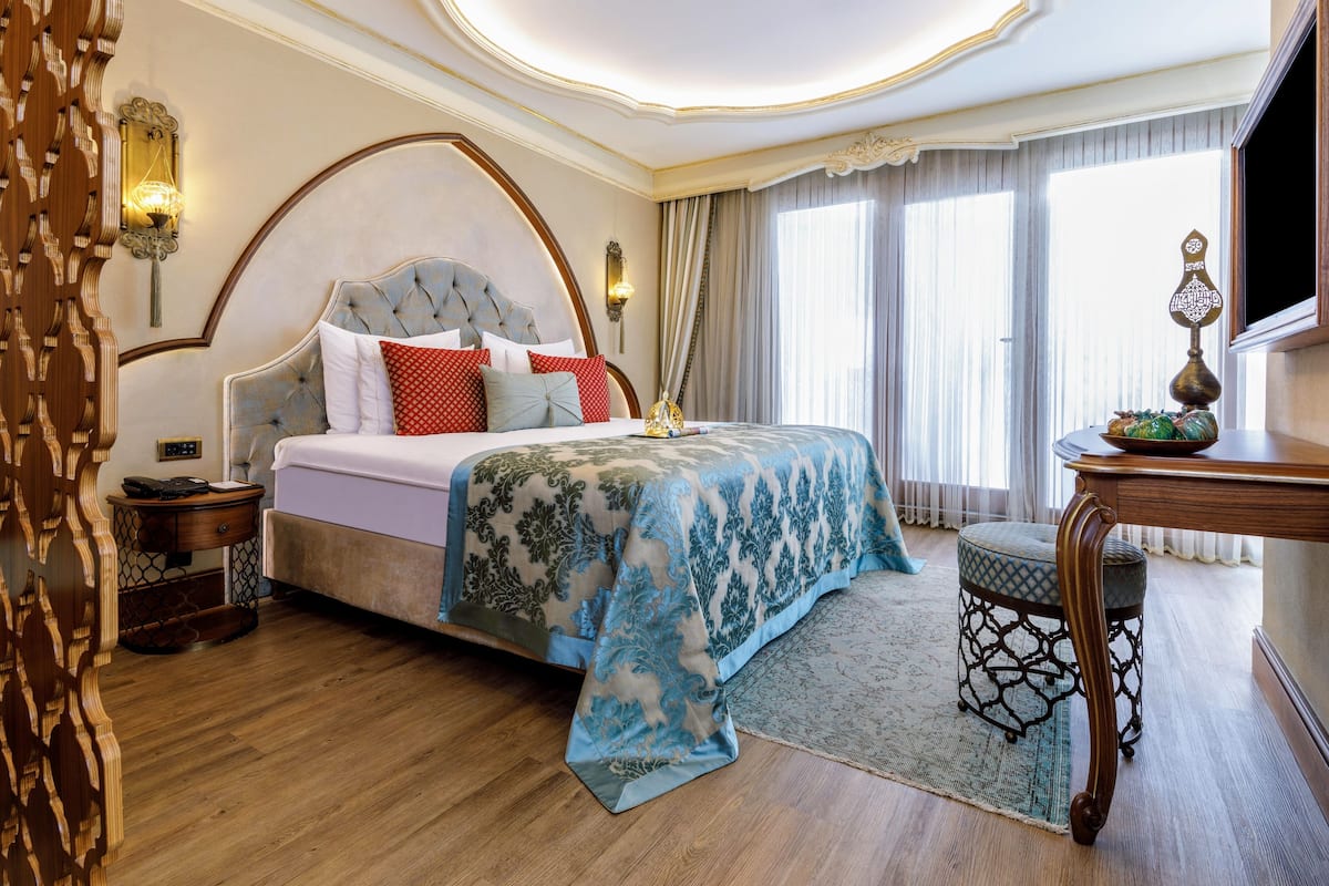 A well-appointed bedroom with a large bed, a nightstand, a wooden side table, and a decorative wall lamp.