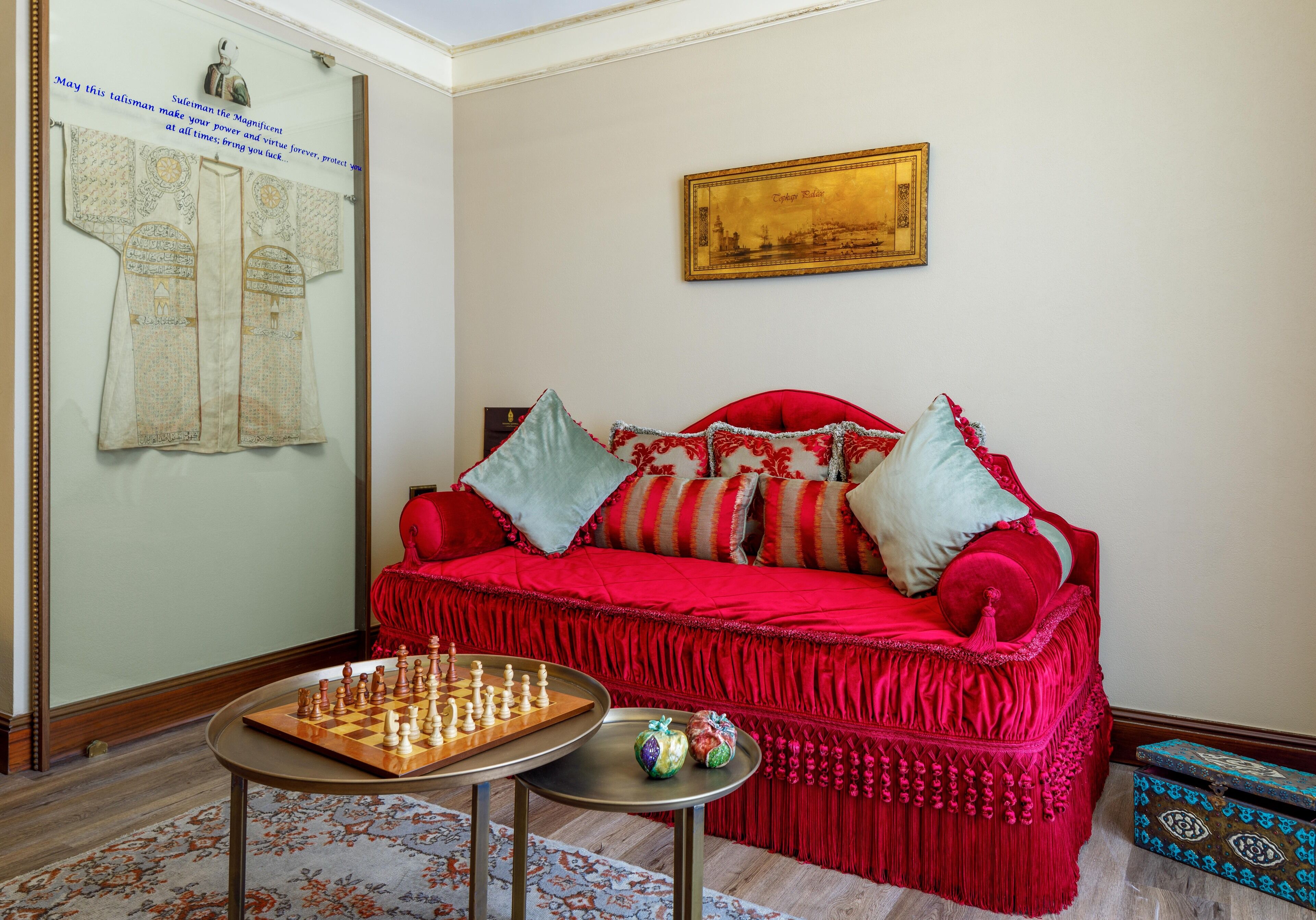 A room with a red sofa, a chessboard, and a framed picture on the wall.