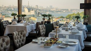 A restaurant with tables set for dining, featuring a city view. - Romance Istanbul Hotel (Istanbul)