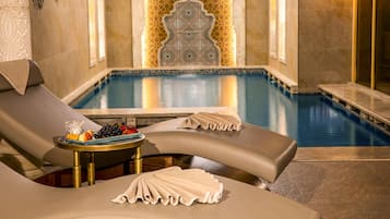 Zona de spa con piscina, sillas de descanso y una pared decorativa.