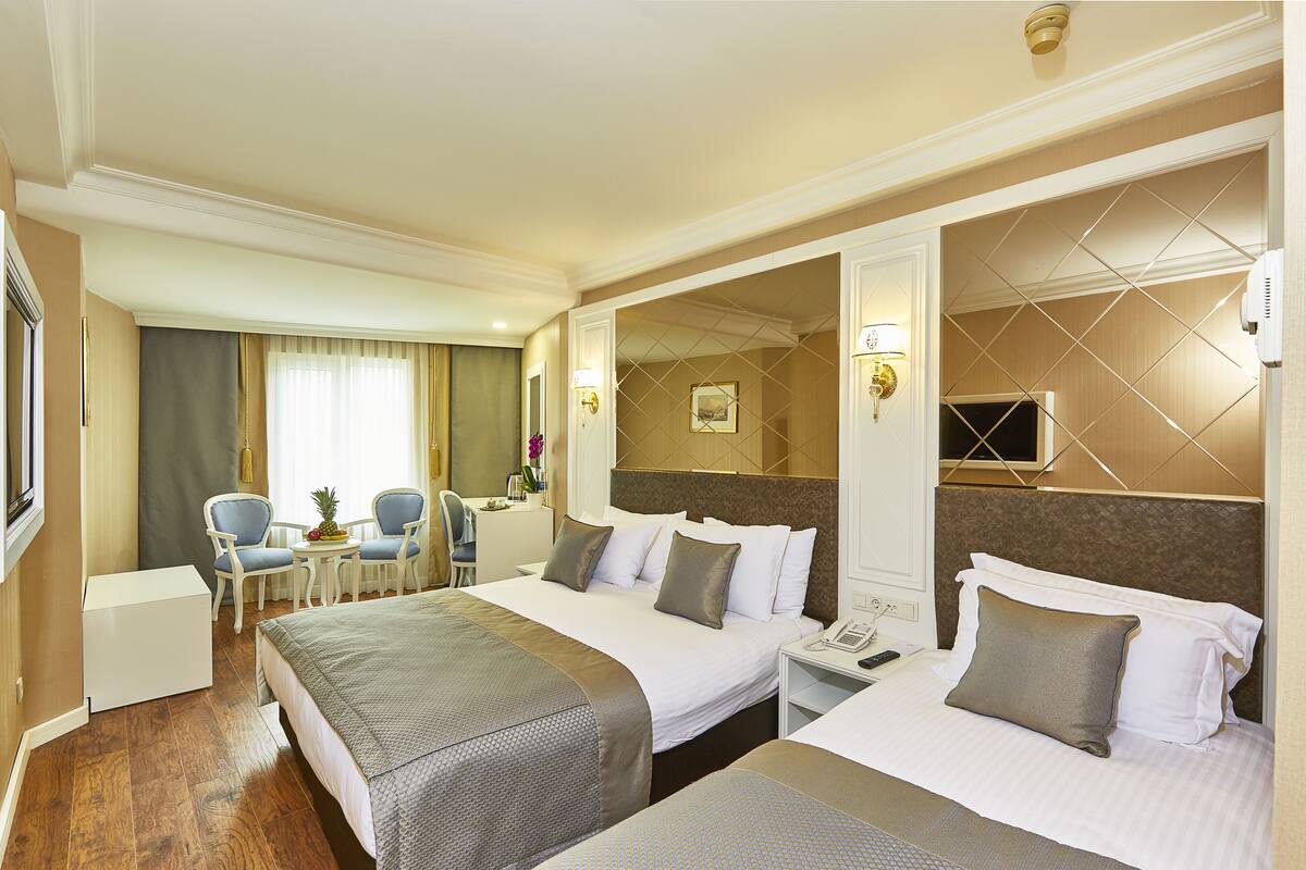 Habitación de hotel con dos camas, un escritorio, sillas y un televisor.