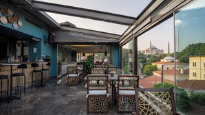 Un restaurante en la azotea con mesas al aire libre, vistas a un edificio histórico y una decoración de diseño moderno.