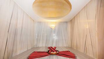 Un cuarto de spa con suelo de mármol, techo de madera y una lámpara fijada a la pared.