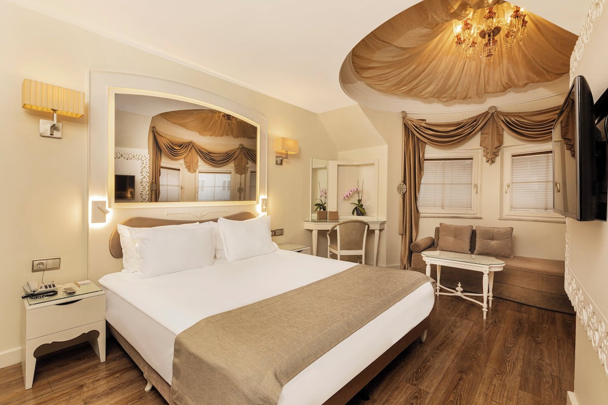 A hotel room with a large bed, a desk, a chair, and a television.