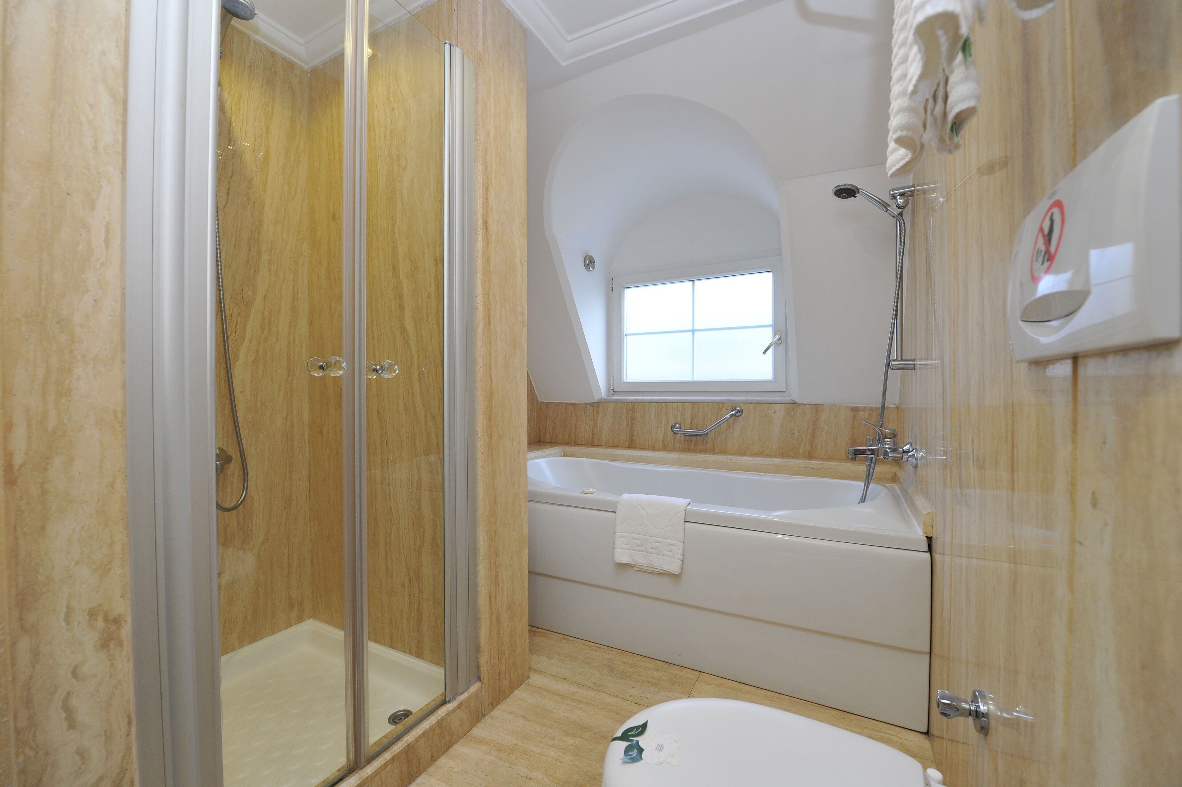 A bathroom with a glass-enclosed shower, a freestanding bathtub, and a window providing natural light.