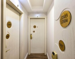 A hallway with a white door, numbered plaques, and a brass door handle.