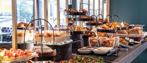Un buffet proposant une variété de plats, notamment des pâtisseries, des desserts et des fruits.